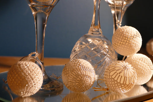Snow Pearl handmade beaded Christmas baubles in white and silver, styled with crystal glassware